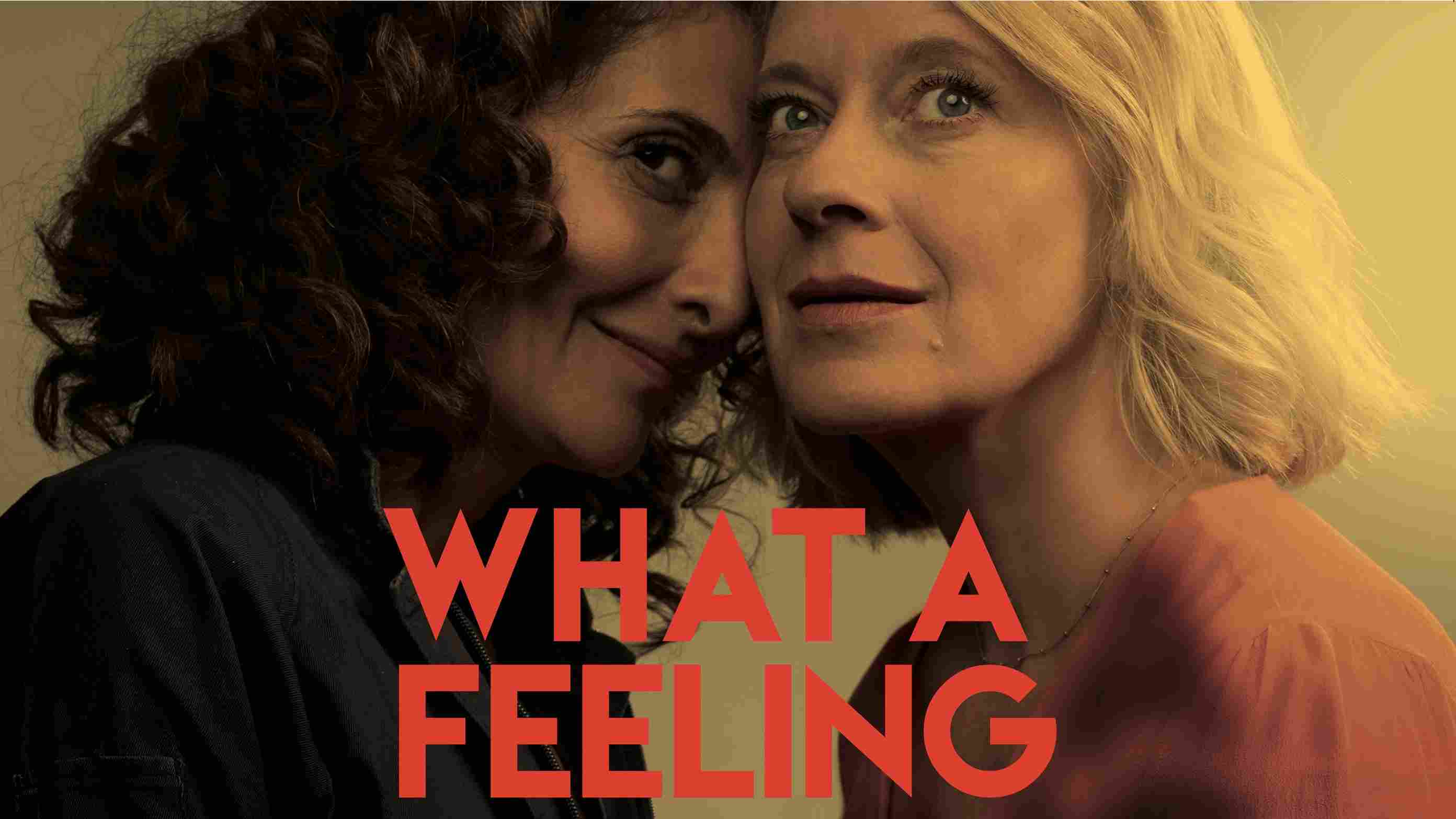 Filmplakat für 'What a Feeling' mit einer Nahaufnahme von zwei Frauen in einem intimen Moment, mit warmen Farben und einem roten Titeltext.