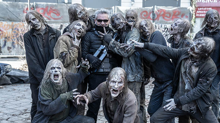 Eine Gruppe Zombie-Darsteller in Make-Up posiert mit dem Regisseur.