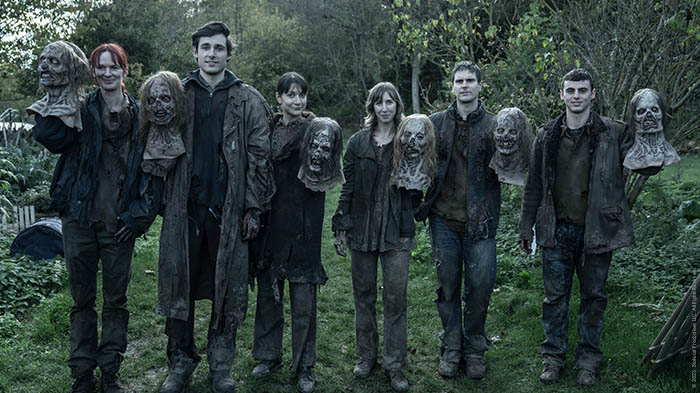 Eine Gruppe Zombie-Darsteller posiert mit ihren hochgehaltenen Zombie-Masken.