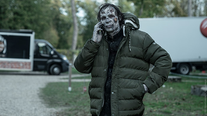 Ein Schauspieler im Zombie-Makeup telefoniert am Handy.