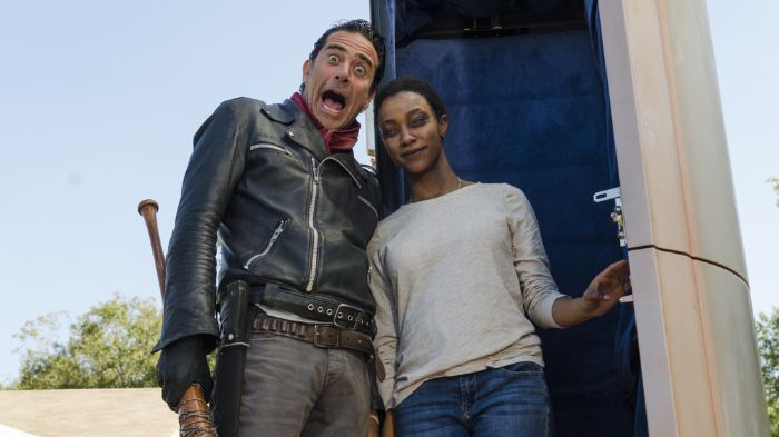 Behind-the-Scenes aus The Walking Dead: Jeffrey Dean Morgan als Negan macht eine übertriebene Grimasse neben Sonequa Martin-Green als Sasha, die mit ruhigem Ausdruck an einer offenen Kapsel steht.