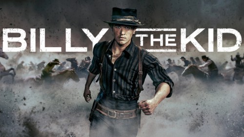 Tom Blyth als Billy the Kid läuft entschlossen durch eine staubige Prärie, Reiter im Hintergrund.