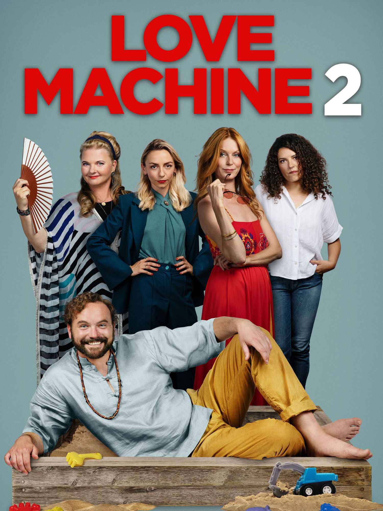 Plakat zur Komödie „Love Machine 2“ mit einem gut gelaunten Mann, der barfuß in einem Sandkasten liegt, während fünf Frauen mit unterschiedlichen Gesichtsausdrücken hinter ihm stehen; der Titel prangt groß in Rot darüber.