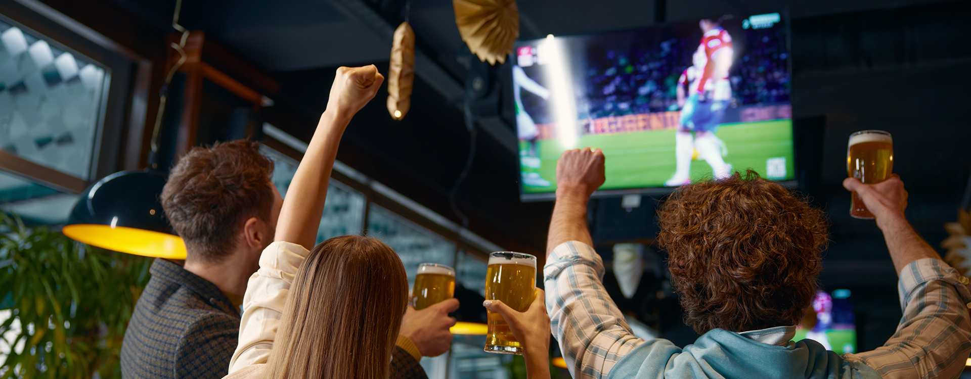 Die drei offiziellen UEFA-Pokale: links der bronzene Europa-League-Pokal, in der Mitte der silberne Champions-League-Pokal und rechts der grüne Conference-League-Pokal, auf einem Fußballrasen mit blauem Hintergrund.